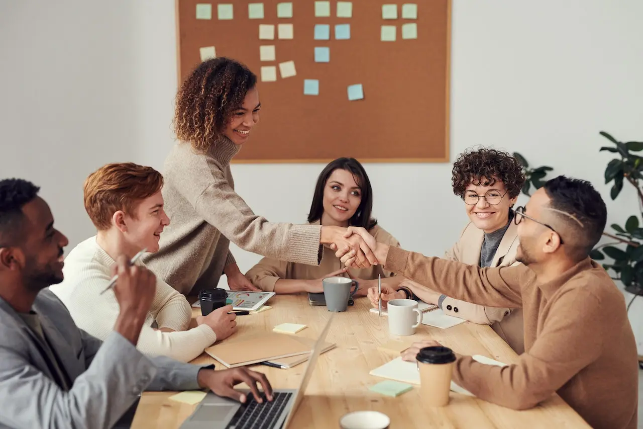 Team shaking hands during the meeting at the table